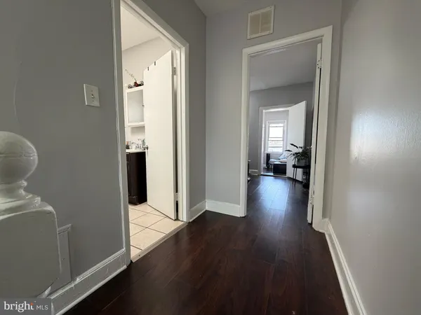 a view of a hallway with wooden floor and a bathroom