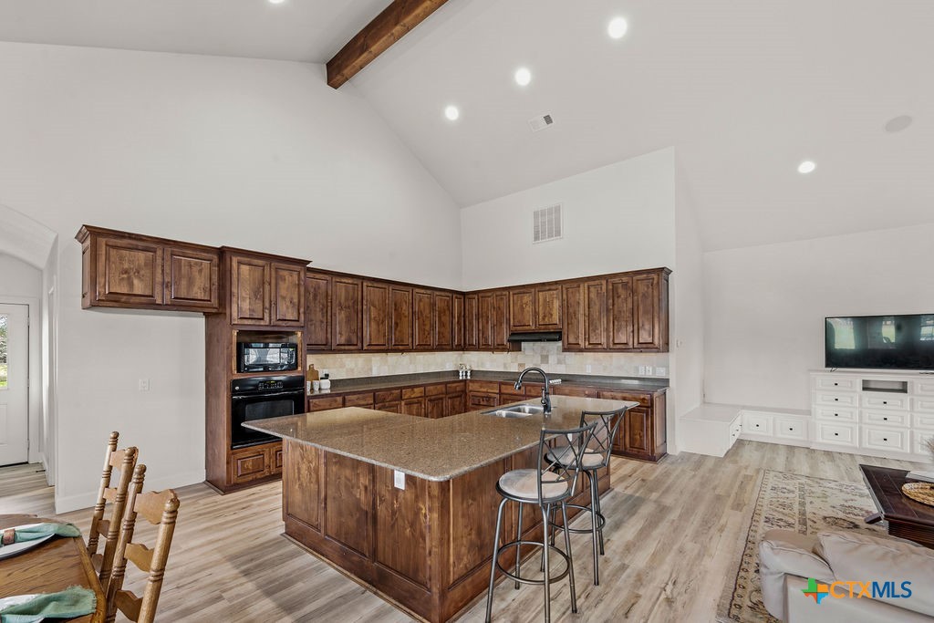 2795 Highway 290 Dripping Springs, TX 78620 - Photo 7 of 40 a kitchen with stainless steel appliances a stove a sink a microwave a dining table and chairs