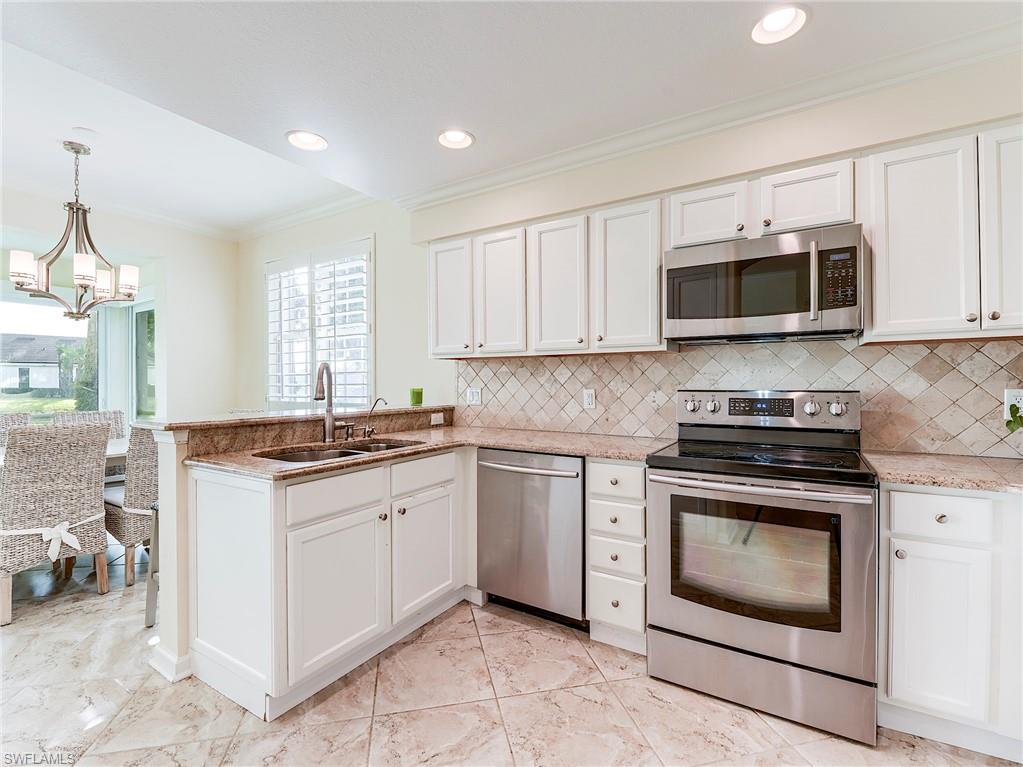 22921 Rosedale Drive, Unit 102 Estero, FL 34135 - Photo 14 of 33 a kitchen with granite countertop a stove top oven microwave and cabinets