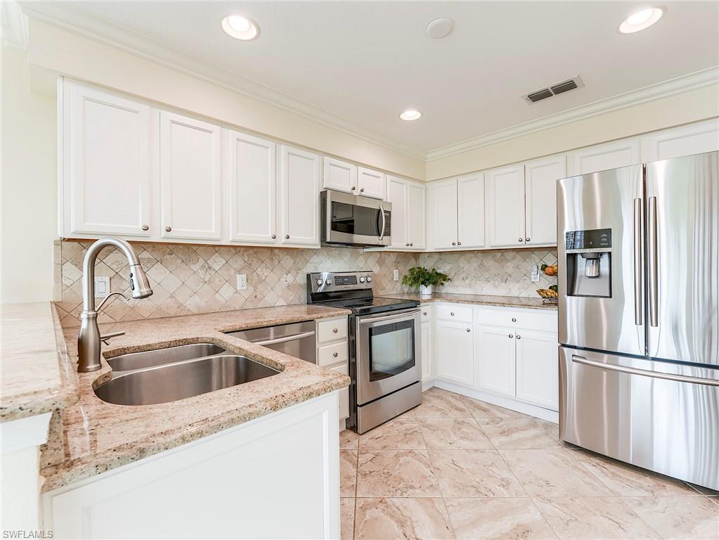22921 Rosedale Drive, Unit 102 Estero, FL 34135 - Photo 16 of 33 a kitchen with white cabinets sink and stainless steel appliances