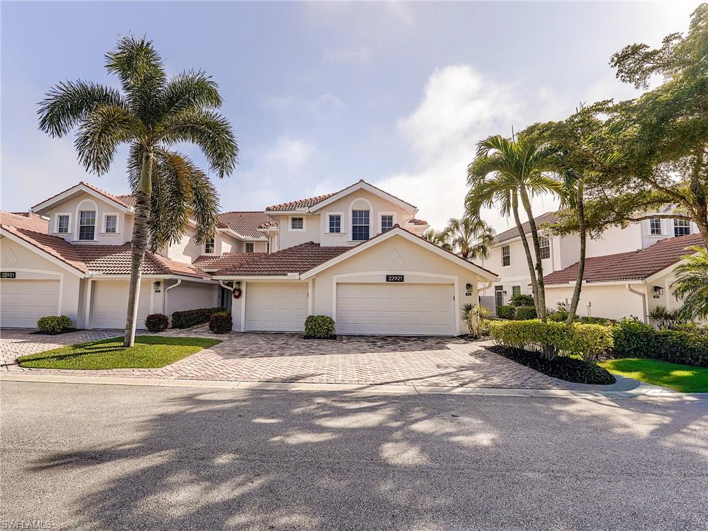 22921 Rosedale Drive, Unit 102 Estero, FL 34135 - Photo 2 of 33 a view of a white house with a big yard and palm trees