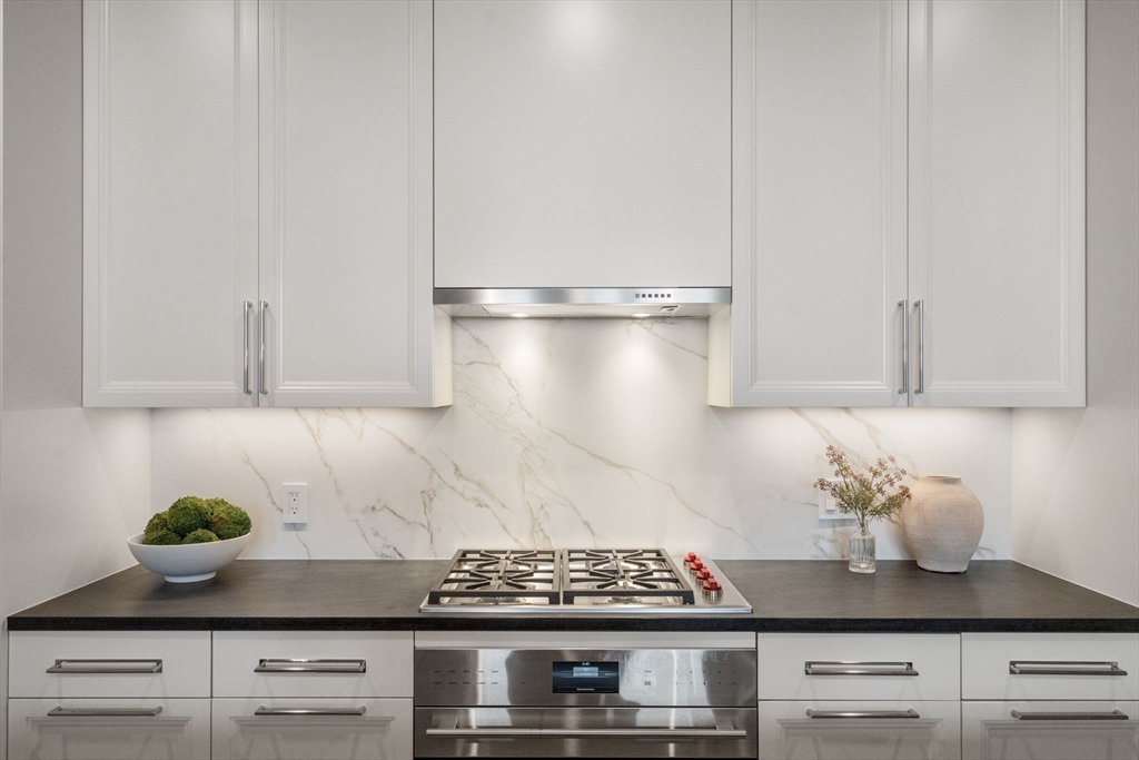 100 Linden Street, Unit 102 Wellesley, MA 02482 - Photo 4 of 30 a kitchen with stainless steel appliances granite countertop white cabinets and a stove