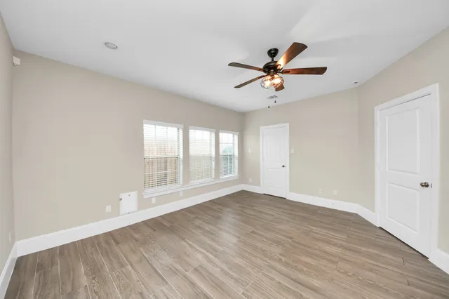 a view of an empty room with a window and a ceiling fan