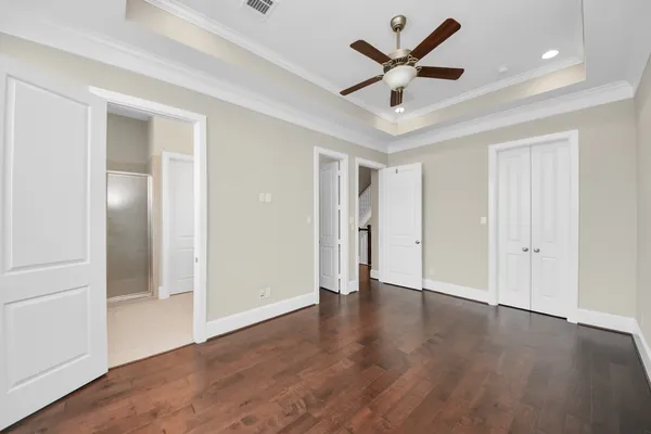 a view of an empty room with wooden floor and a ceiling fan
