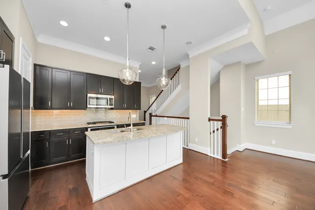 a kitchen with stainless steel appliances granite countertop a sink a stove and a wooden floors