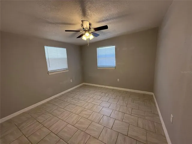 a view of a livingroom with a chandelier fan and windows