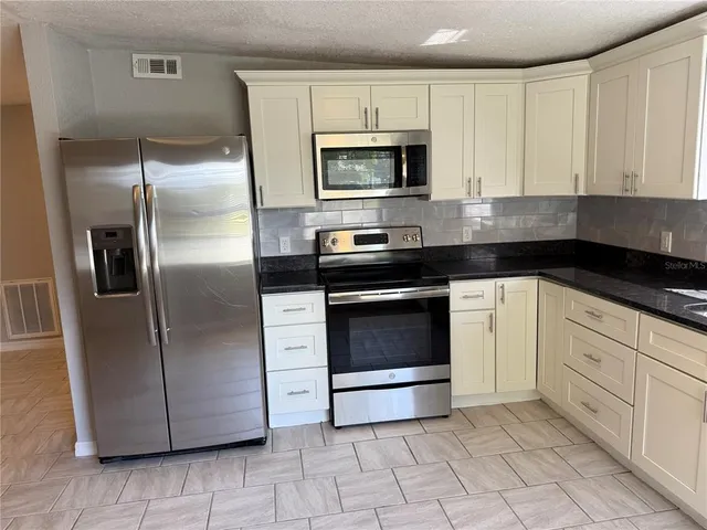 a kitchen with stainless steel appliances granite countertop a sink a stove a refrigerator a microwave and cabinets