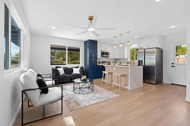 a kitchen with stainless steel appliances kitchen island granite countertop a refrigerator a stove top oven a dining table and chairs with wooden floor