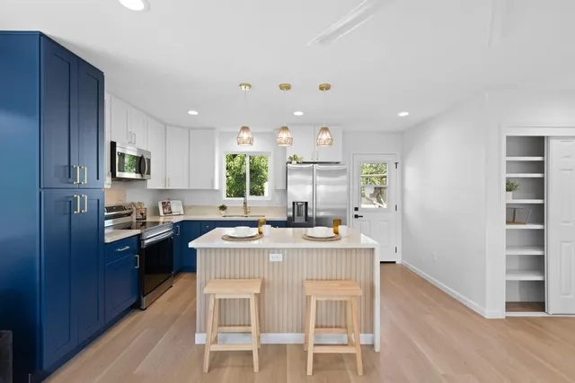 a kitchen with kitchen island granite countertop a sink stove and refrigerator
