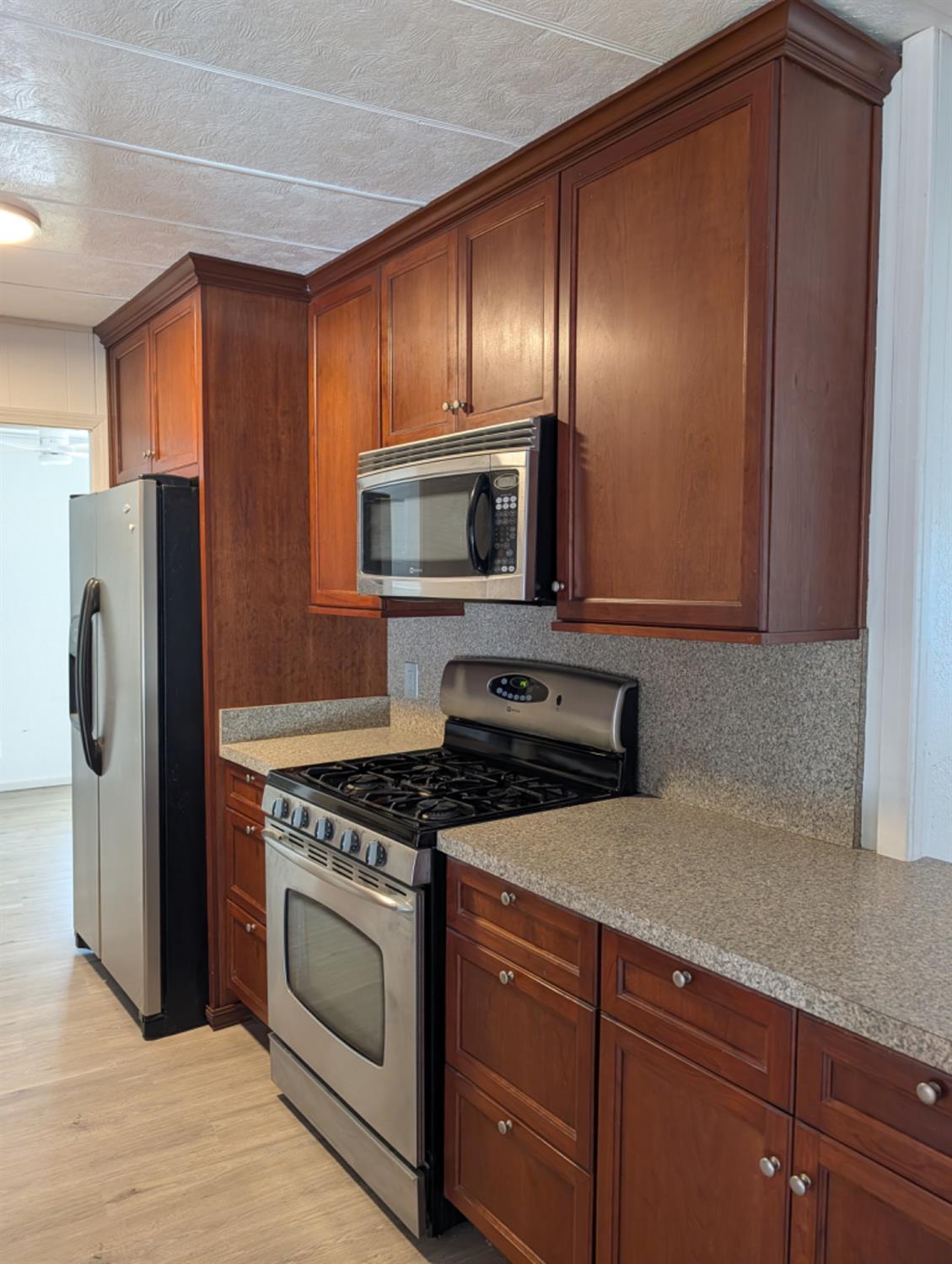 9484 99 Frontage Road, Unit 36 Stockton, CA 95212 - Photo 6 of 8 a kitchen with granite countertop stainless steel appliances and wooden cabinets