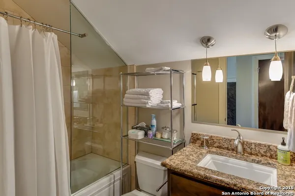 a bathroom with a granite countertop sink a mirror a bathtub and shower