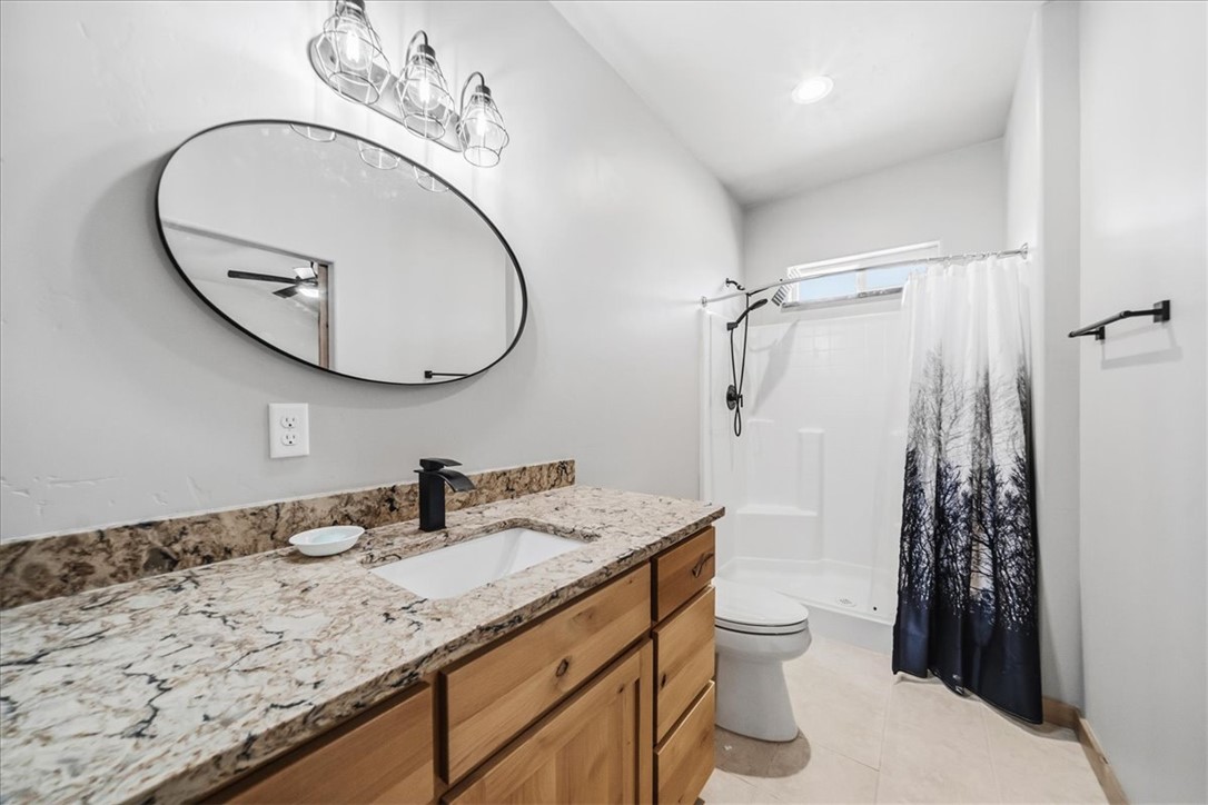 10374 East Happy Trails Road Kingman, AZ 86401 - Photo 36 of 68 a bathroom with a granite countertop sink a toilet and a mirror