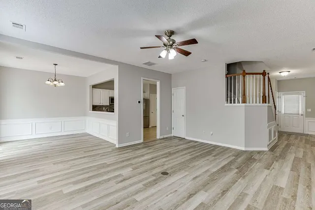a view of empty room with wooden floor and ceiling fan