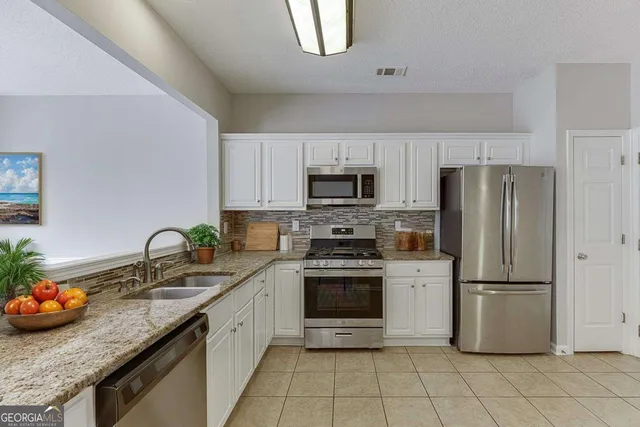 a kitchen with granite countertop a sink stainless steel appliances and cabinets