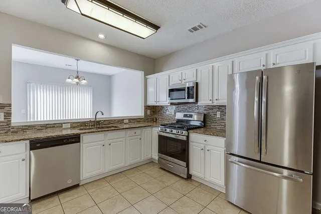a kitchen with white cabinets stainless steel appliances and a sink