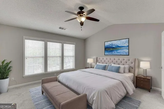 a spacious bedroom with a large bed chandelier and a window