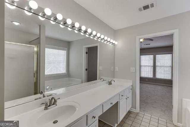 a spacious bathroom with a double vanity sink a large mirror and shower