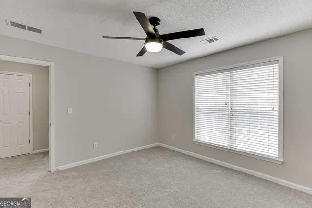 an empty room to ceiling fan and closet area
