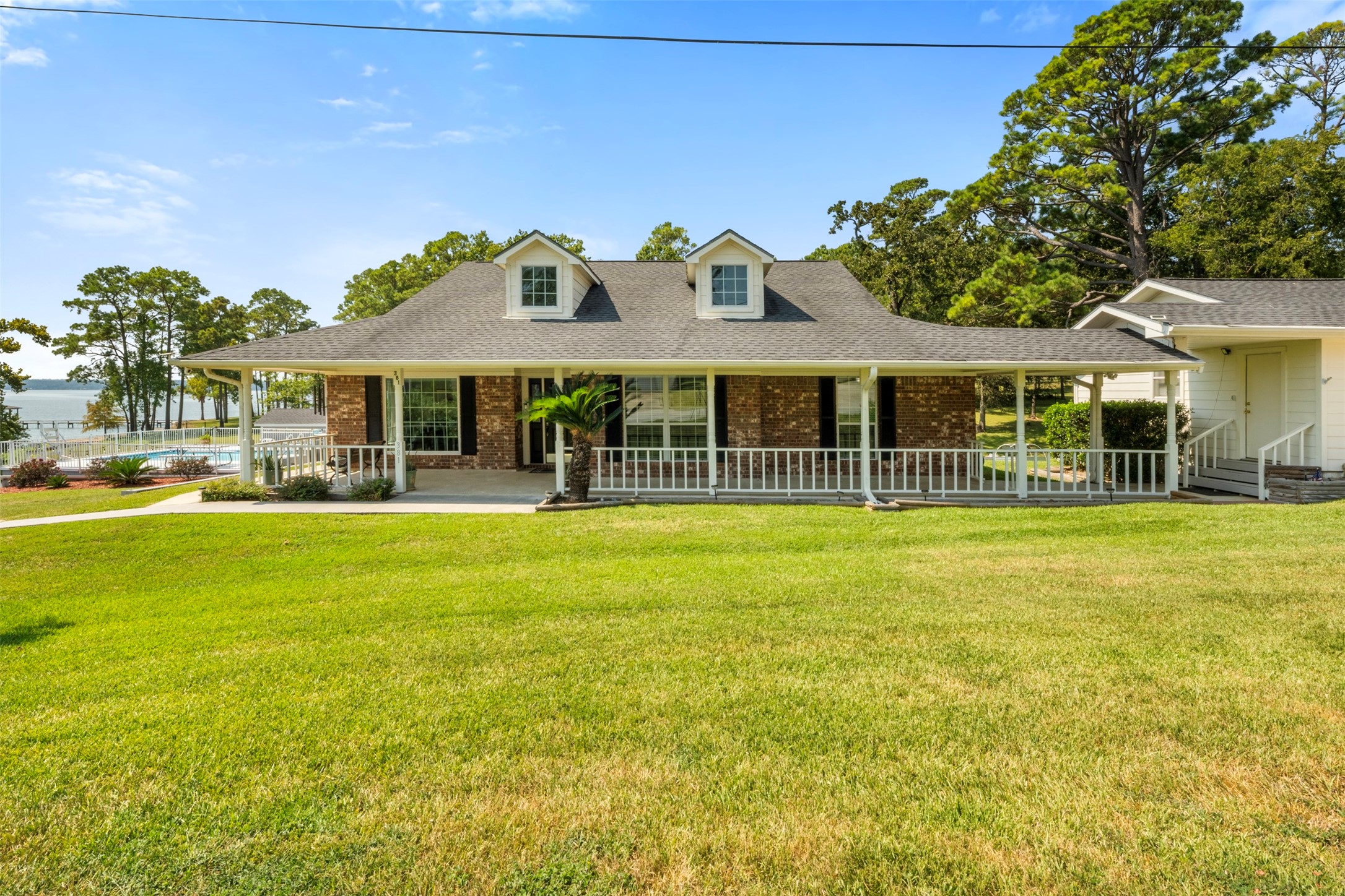 Classic curb appeal with a wide front porch and charming windows. The landscaped lawn leads up to this brick beauty, perfectly positioned near the water. Relax on the wraparound porch and soak in the peaceful setting.
