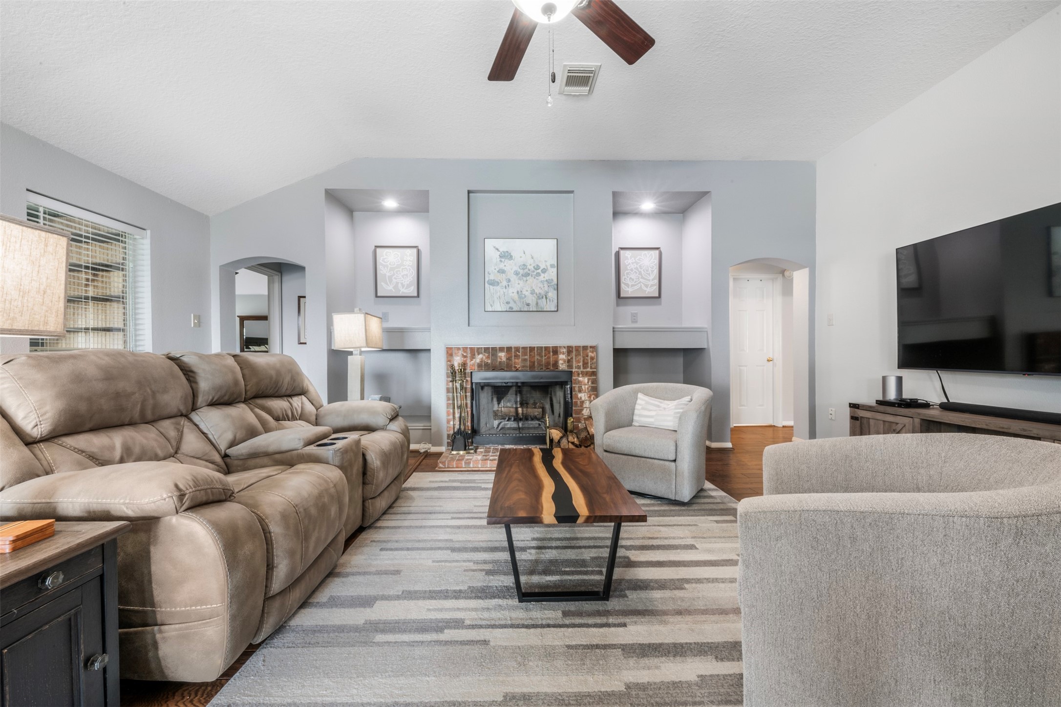 381 West Lake Drive Point Blank, TX 77364 - Photo 12 of 33 Enjoy cozy evenings in front of the brick fireplace accented with custom niches and built-in lighting. This inviting living space offers a balance of warmth and elegance, ideal for both relaxing nights in and hosting guests.