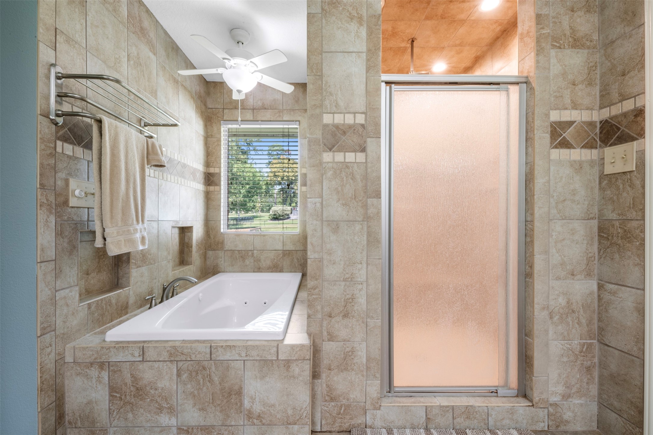 381 West Lake Drive Point Blank, TX 77364 - Photo 16 of 33 The primary bath features a relaxing jetted tub & walk-in shower. A picture window brings in natural light, creating a soothing retreat for daily unwinding.