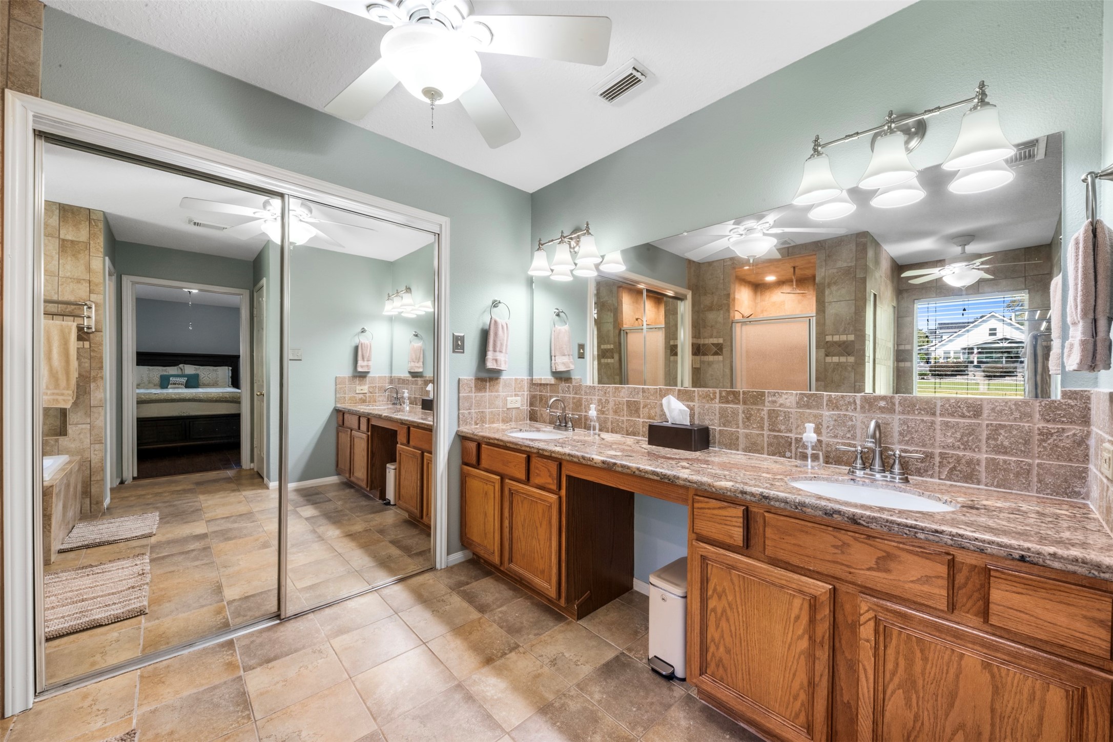 381 West Lake Drive Point Blank, TX 77364 - Photo 17 of 33 This ensuite bath offers dual vanities with granite counters, a large mirror, and a spacious layout. The design provides plenty of storage and convenience, with a seamless flow to the bedroom.