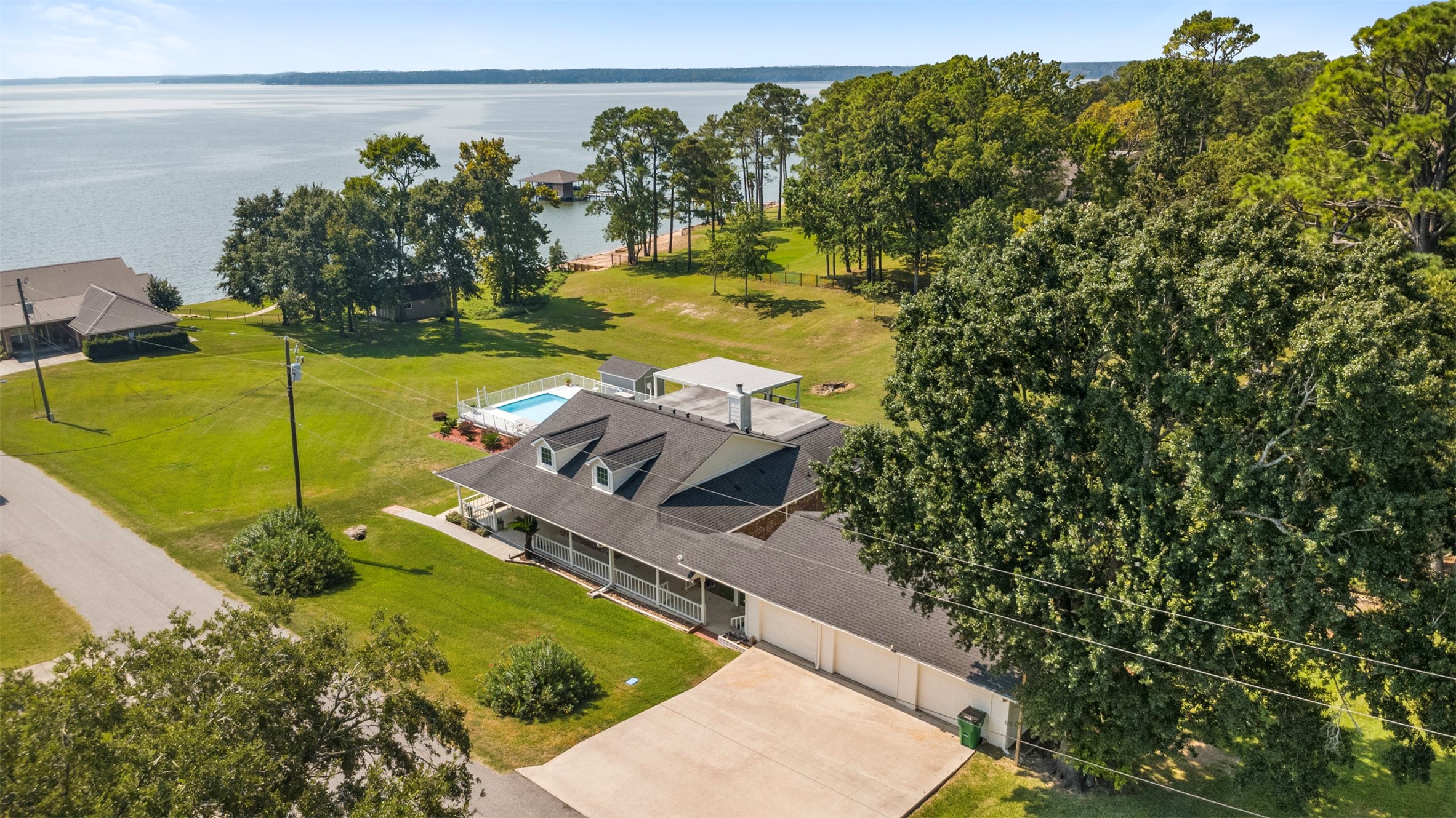 381 West Lake Drive Point Blank, TX 77364 - Photo 2 of 33 This lakeside property offers incredible views and ample space to enjoy outdoor living. From above, you can see the expansive lot, refreshing pool, wraparound porch, and direct proximity to Lake Livingston — all in one stunning shot.
