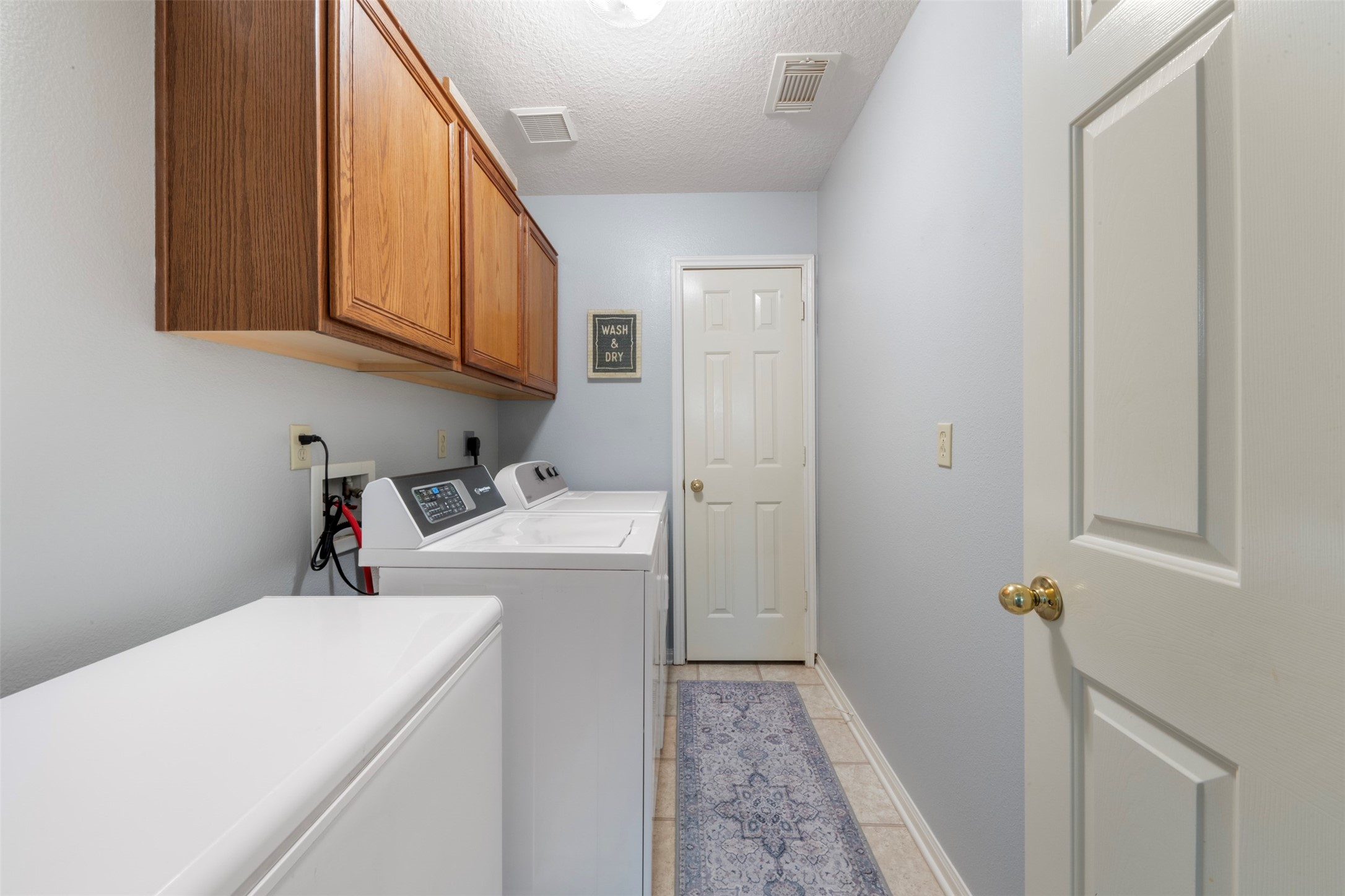 381 West Lake Drive Point Blank, TX 77364 - Photo 21 of 33 Functional and convenient laundry space with upper cabinetry for storage, tile floors, and room for a full washer/dryer set. Plenty of space for a freezer.