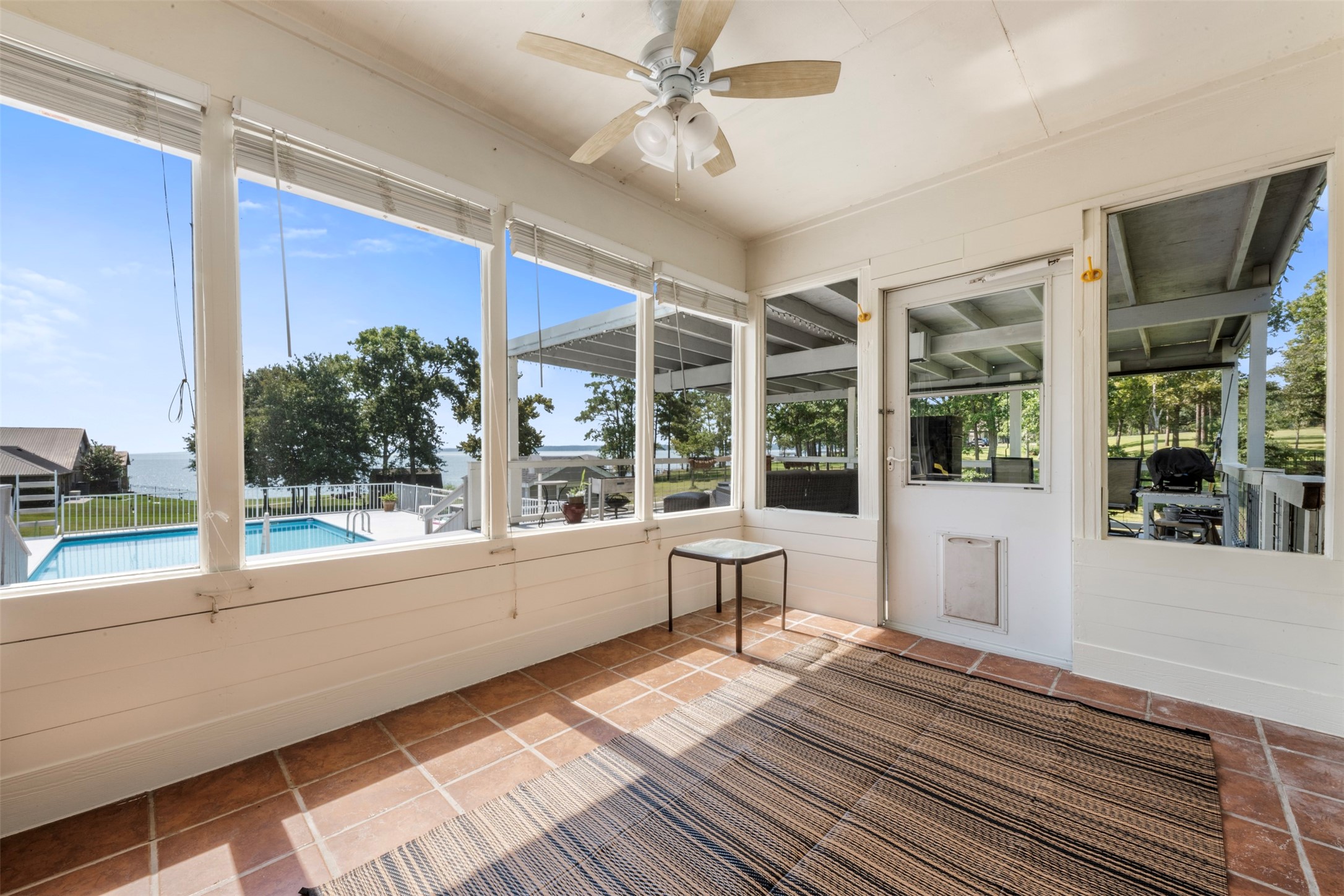 381 West Lake Drive Point Blank, TX 77364 - Photo 22 of 33 Enjoy stunning views of the pool and lake from the tiled sunroom. Large windows fill the space with natural light, making it a perfect indoor/outdoor transition area.