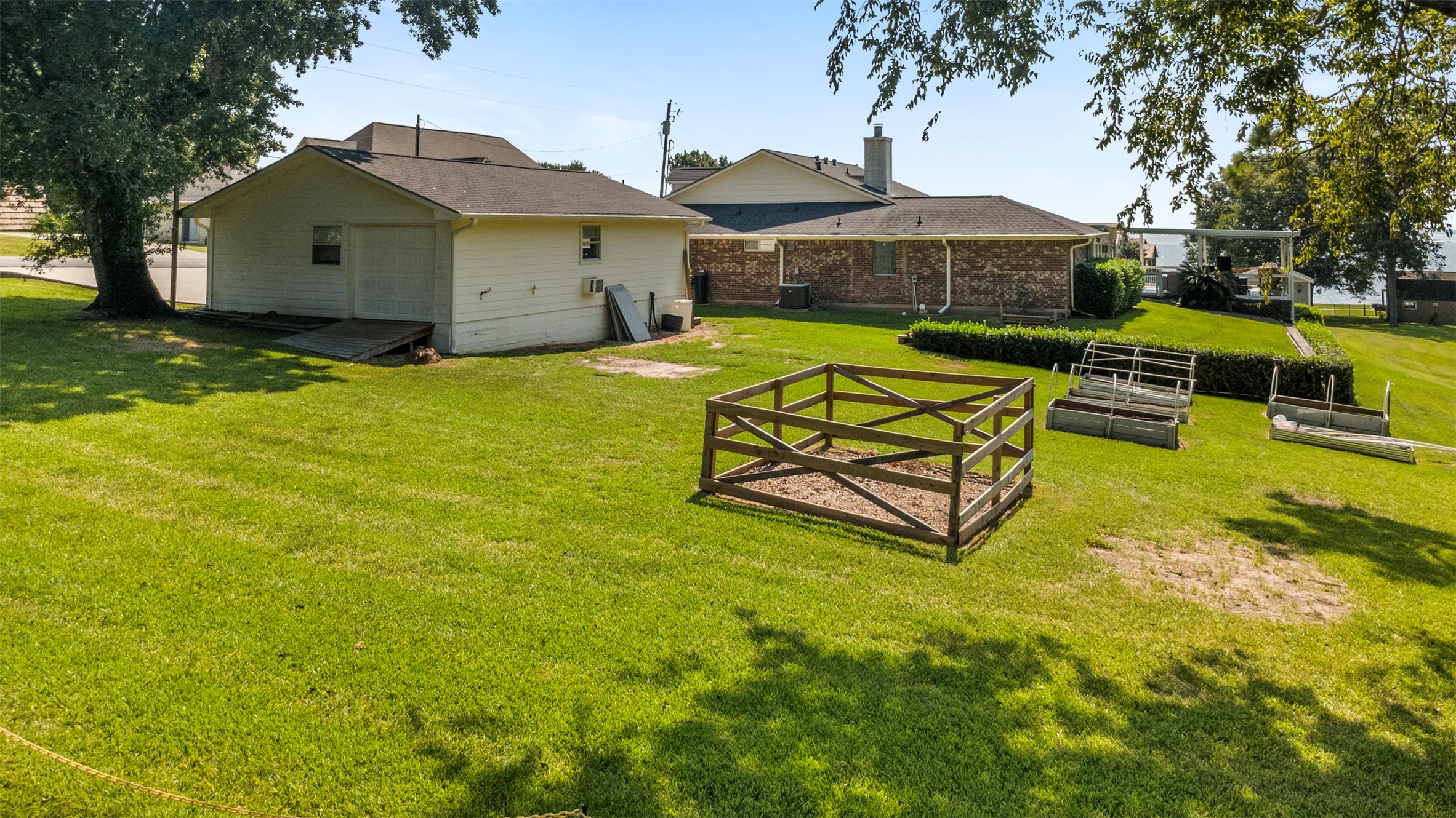381 West Lake Drive Point Blank, TX 77364 - Photo 30 of 33 A spacious backyard with a detached workshop/garage, raised garden beds, and plenty of open green space. Perfect for hobbies, storage, or cultivating your own garden retreat.
