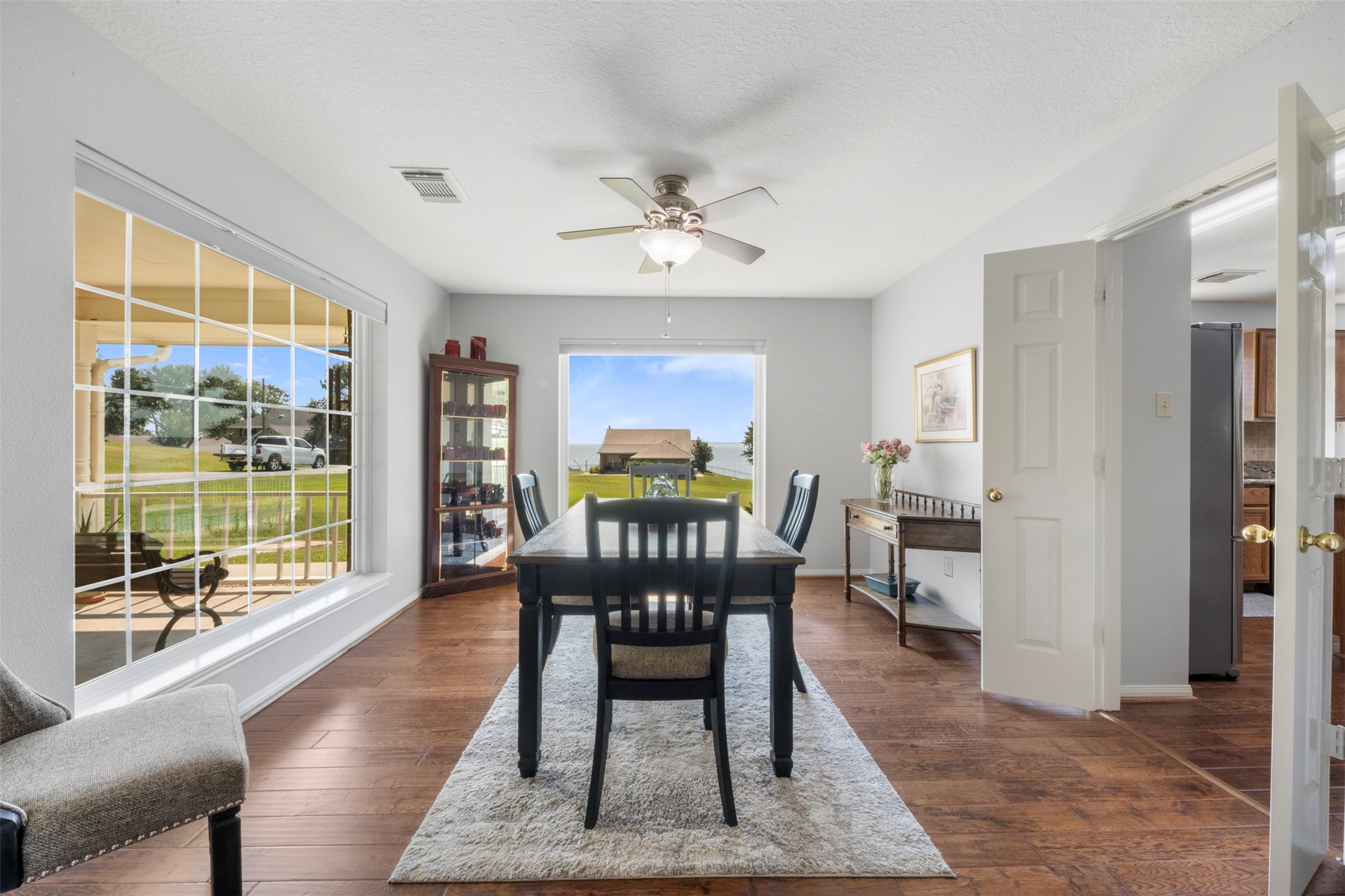 381 West Lake Drive Point Blank, TX 77364 - Photo 4 of 33 Natural light pours into this elegant dining room, framed by oversized windows that capture stunning lake views. With rich wood flooring & neutral tones, this space sets the stage for memorable meals and gatherings.