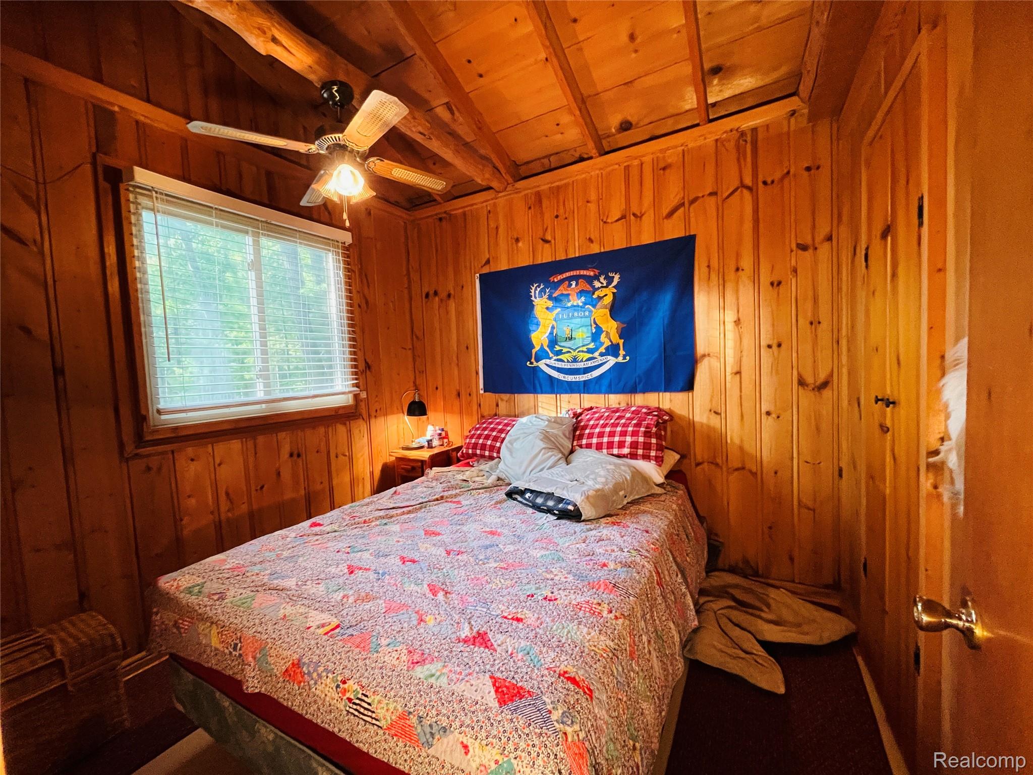 417 Ogemaw Road Rose City, MI 48654 - Photo 7 of 26 Wood-paneled room with a window, ceiling fan with light, and a built-in closet with a wood door