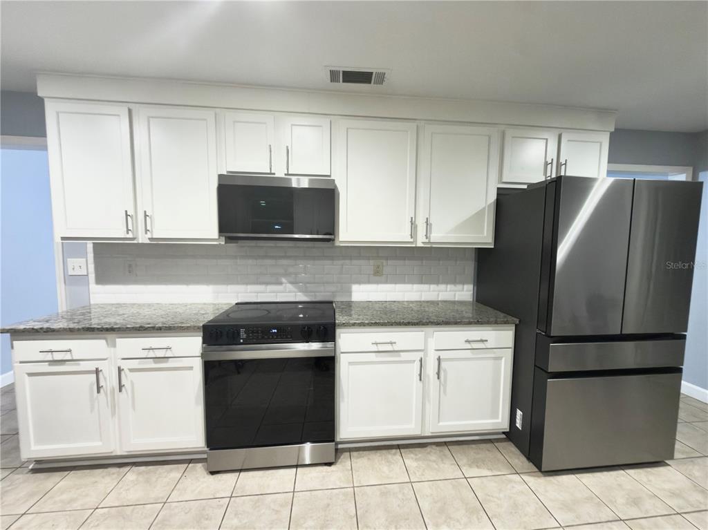9989 Leahy Road Jacksonville, FL 32246 - Photo 3 of 21 a kitchen with white cabinets and stainless steel appliances