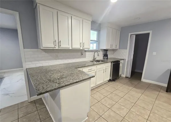 a kitchen with a sink dishwasher stove and white cabinets