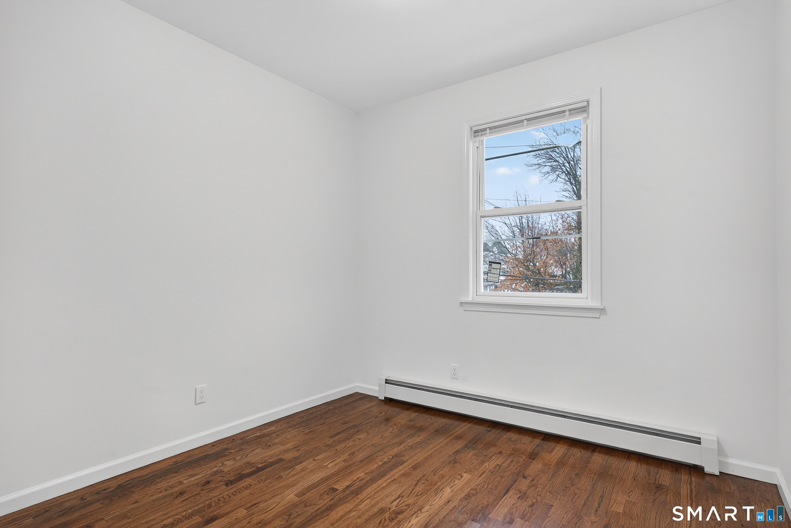 144 Cottage Street, Unit 2 Bridgeport, CT 06605 - Photo 4 of 12 a view of an empty room with wooden floor and a window
