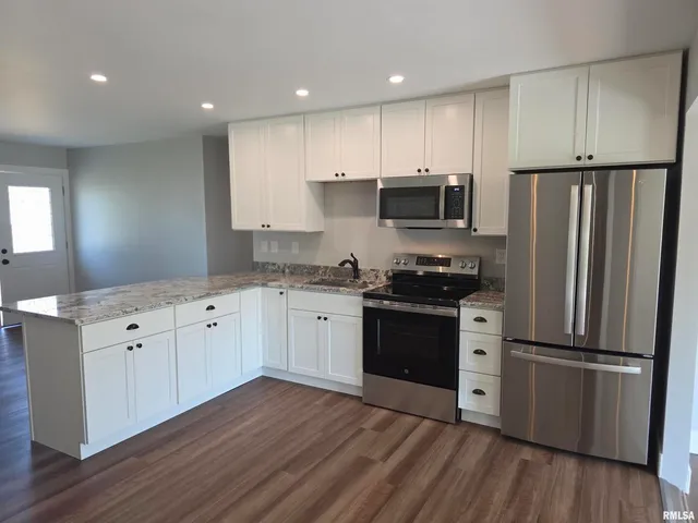 a kitchen with granite countertop a refrigerator stove and wooden floor
