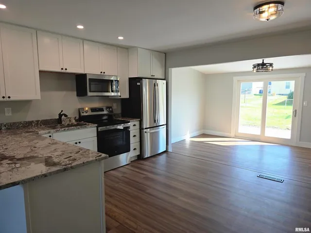 a kitchen with wooden floors a refrigerator and a stove top oven