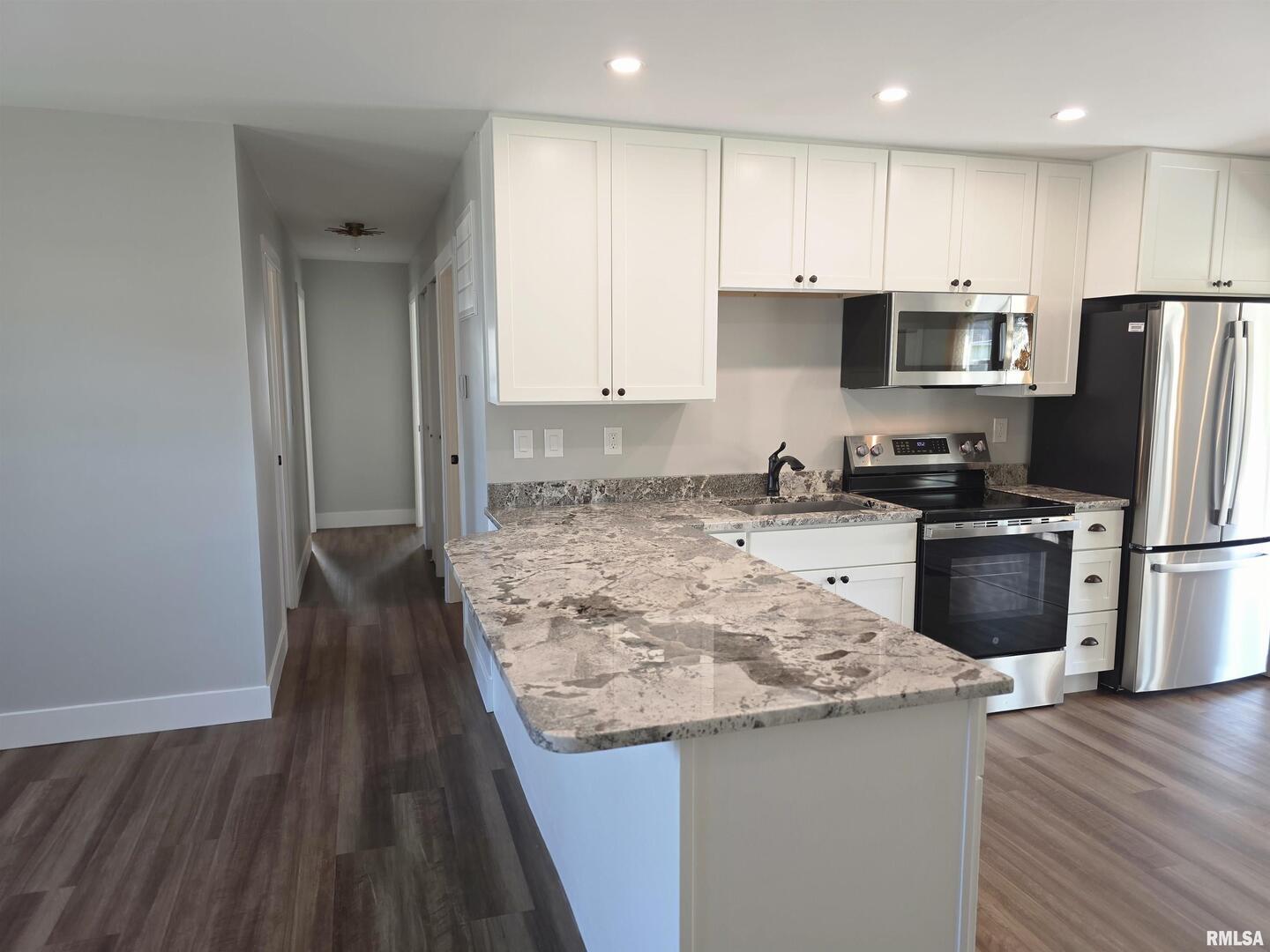 1031 Galbraith Drive Clinton, IA 52732 - Photo 9 of 35 a kitchen with kitchen island granite countertop a stove a sink a refrigerator and white cabinets with wooden floor