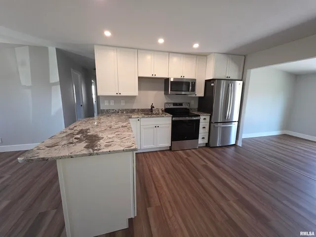 a kitchen with stainless steel appliances granite countertop a refrigerator a stove and a wooden floors