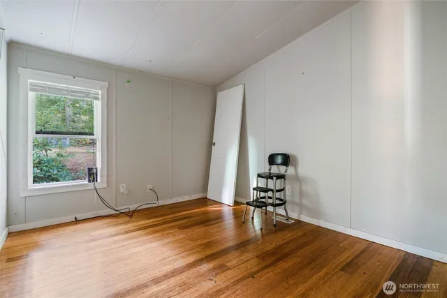 a view of a room with wooden floor a piano and windows