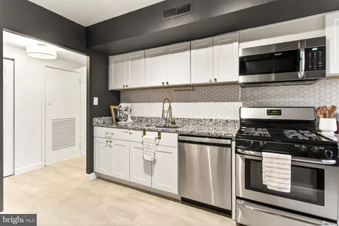 a kitchen with stainless steel appliances granite countertop white cabinets stove a sink and dishwasher
