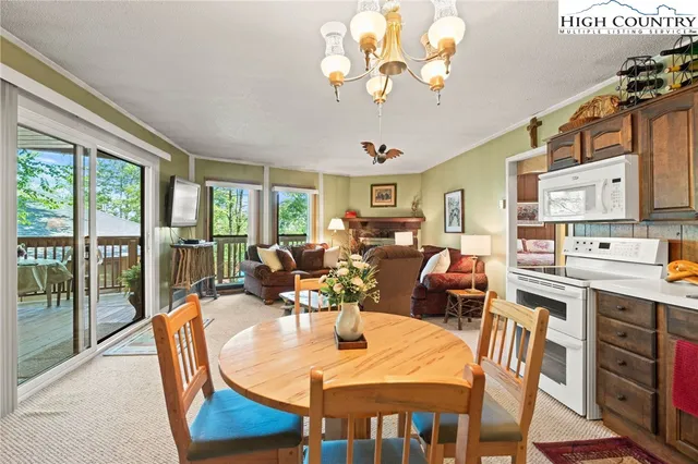 a view of a dining room with furniture a chandelier and large windows