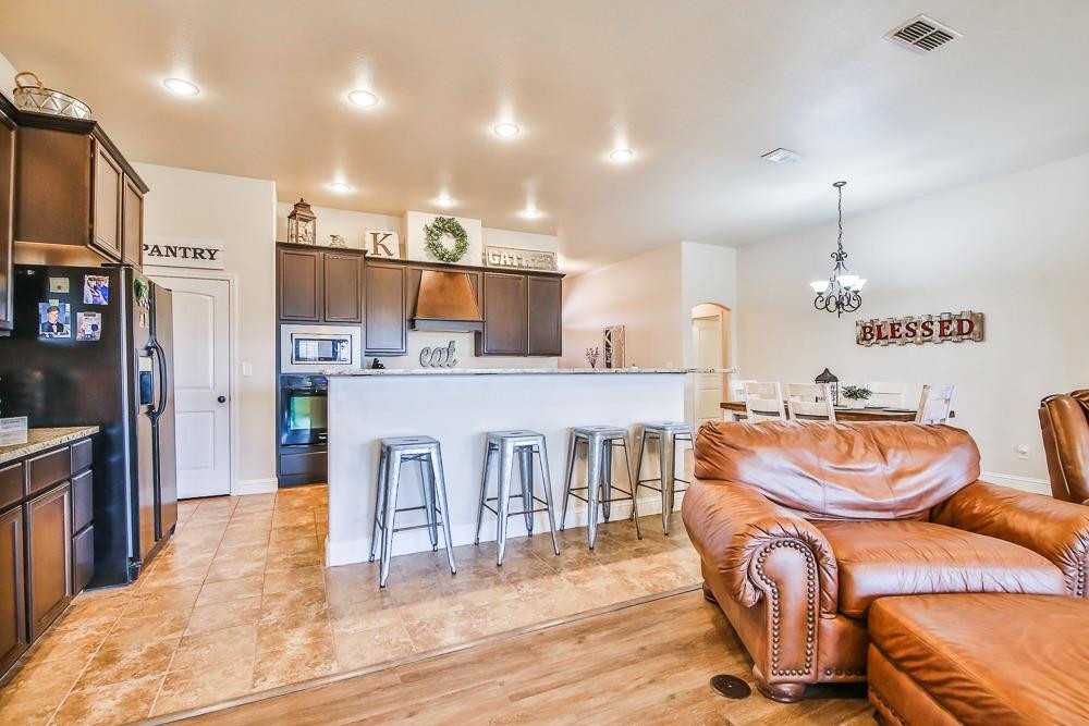 9103 Rochester Avenue Lubbock, TX 79424 - Photo 9 of 26 a kitchen with stainless steel appliances kitchen island granite countertop a refrigerator and a stove
