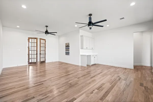 a view of empty room with wooden floor and ceiling fan
