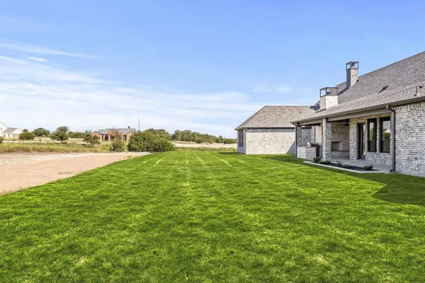 a aerial view of a house next to a big yard with plants and large trees