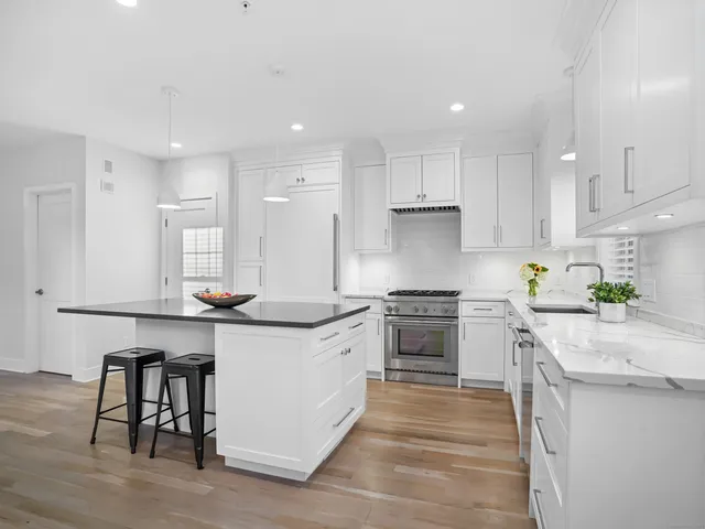 a kitchen with stainless steel appliances granite countertop a stove top oven a sink dishwasher and a refrigerator with wooden floor