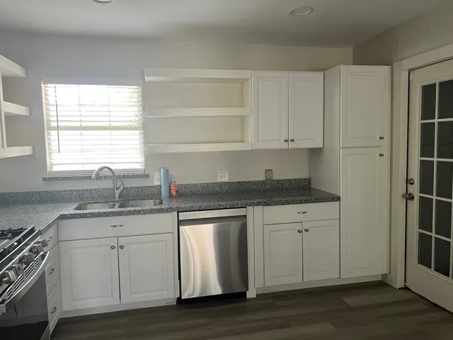 a kitchen with granite countertop white cabinets and a sink