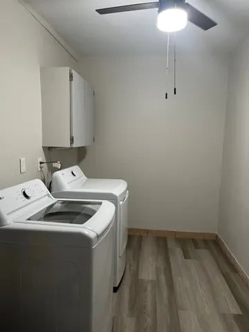 an empty room with a chandelier fan and windows