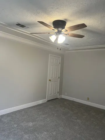 an empty room with a chandelier fan and windows