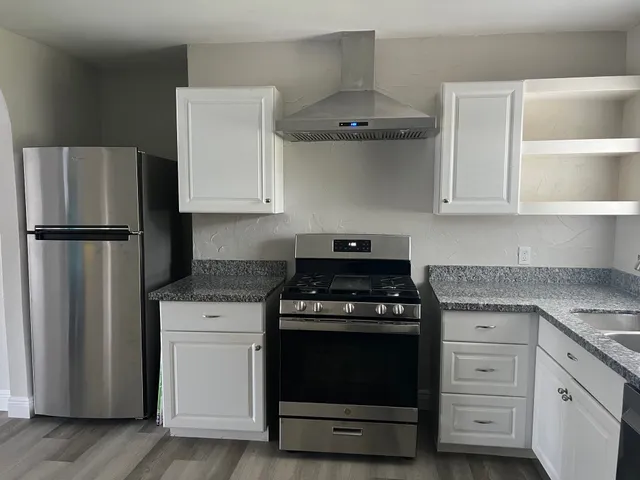 a kitchen with stainless steel appliances granite countertop a stove a refrigerator and a sink